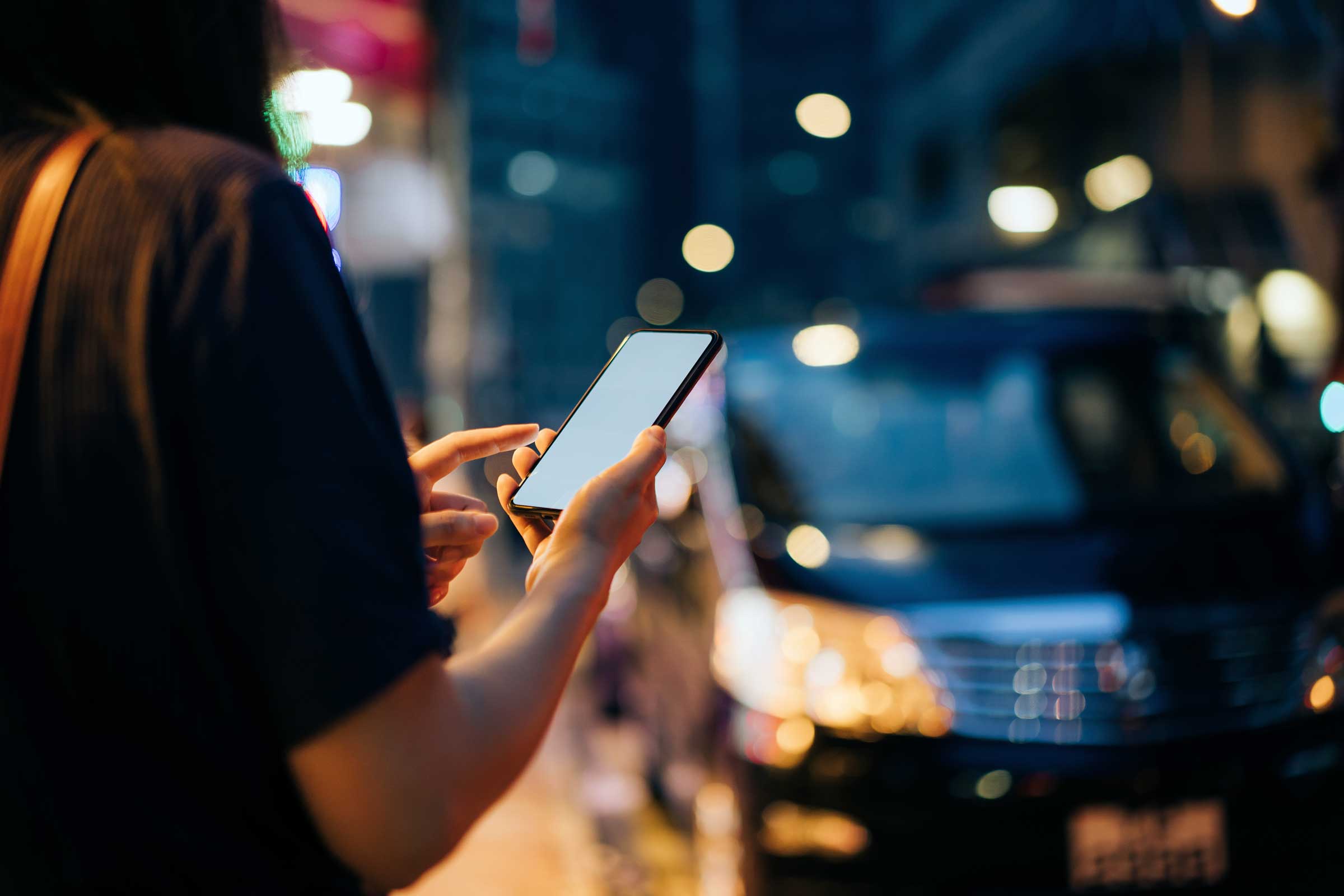 Person using a mobile phone at night while waiting for her ride 