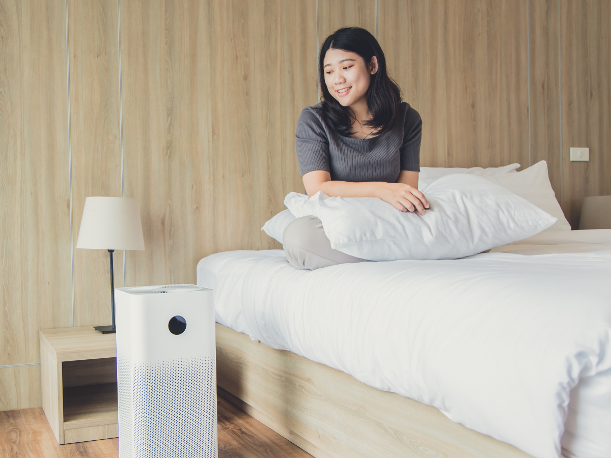 Person sitting on their bed while using an air purifier